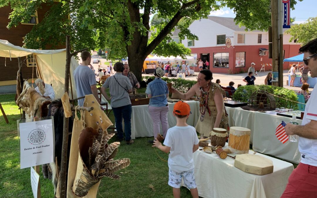 Table displaying Abenaki artifacts with an indigenous presenter demonstrating fletching