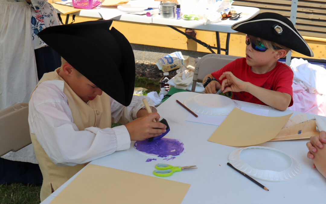 Children wearing tricorn hats making their own stamps on paper plates