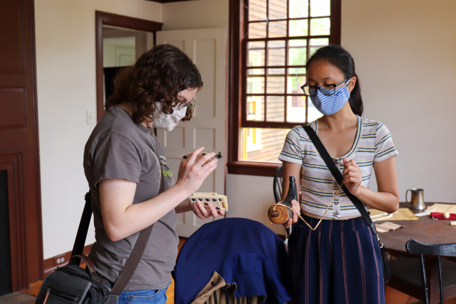 Two visitors pick up reproduction 18th century items in the Folsom Tavern