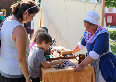 A reenactor from the Acton Minutemen challenges a child to a game of checkers. The outcome is yet to be determined.
