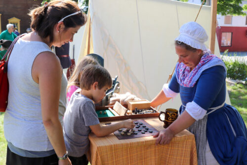 A reenactor from the Acton Minutemen challenges a child to a game of checkers. The outcome is yet to be determined.