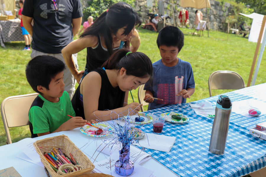 A family of four use paint to decorate rocks of the liberty herb garden
