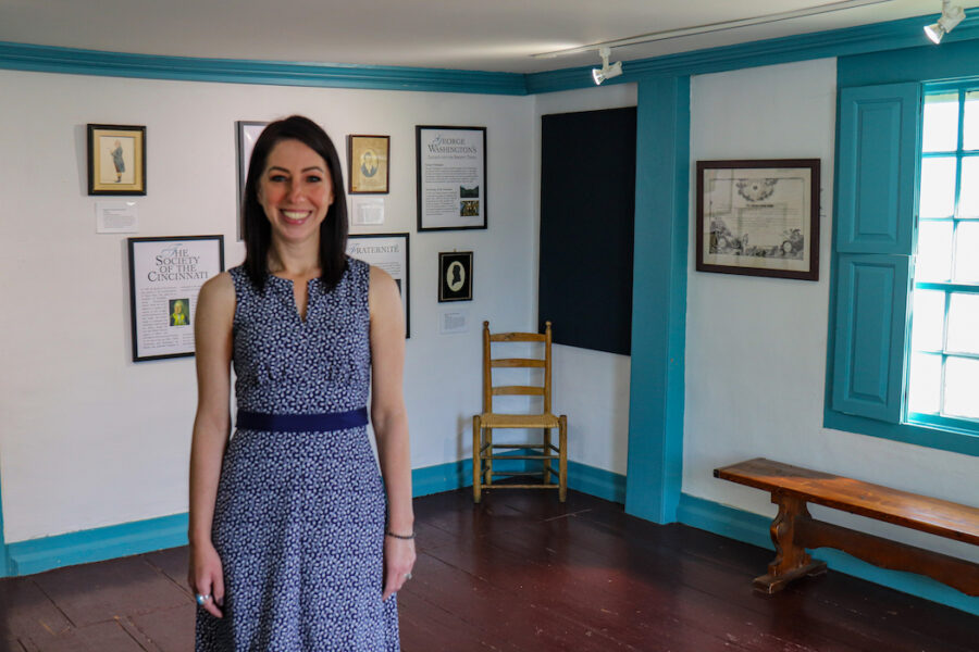 Acting Executive Director Jen Carr stands in the Fogg Room, a room with collections items on the walls, but no museum case in it.