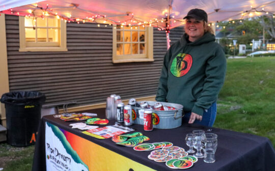 Brewer from Pipe Dream Brewery in Londonderry standing behind a table full of their beers and merchandise.
