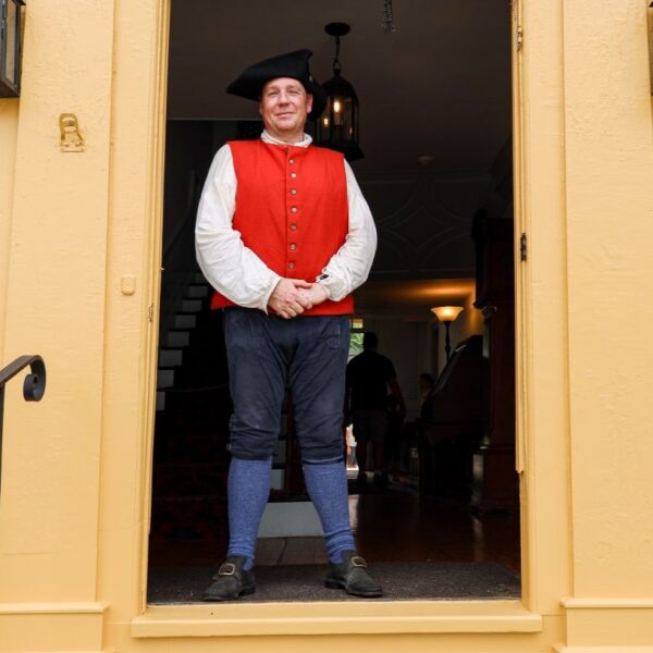 man in 18th Century clothing standing in historical doorway